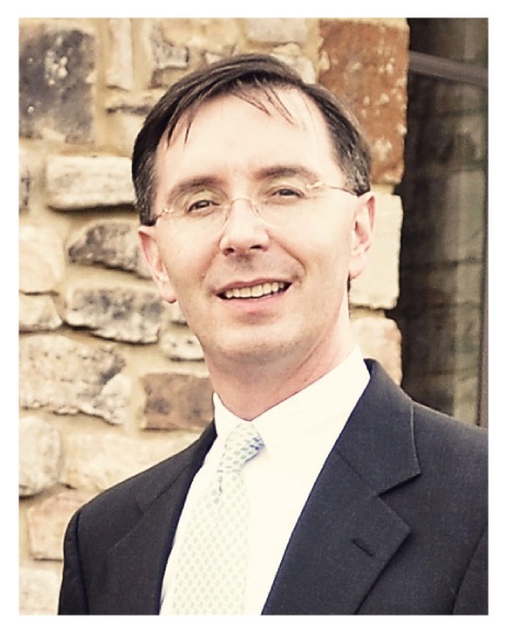 A man in suit and tie smiling for the camera.