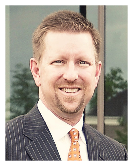 A man in a suit and tie smiling for the camera.