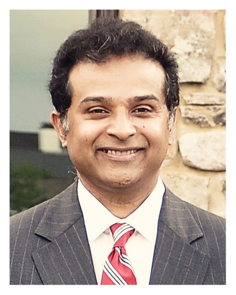 A man in a suit and tie smiling for the camera.